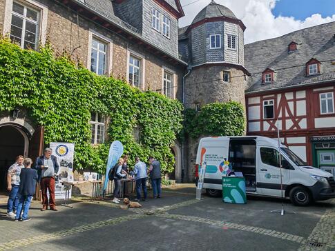 Mehrere Personen stehen an Infost&auml;nden im Hof vor dem Museumsgeb&auml;ude 