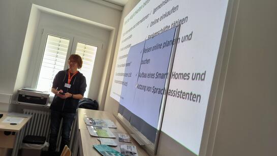 Referent Johannes steht vor einer auf die Wand projizierten Pr&auml;sentation 