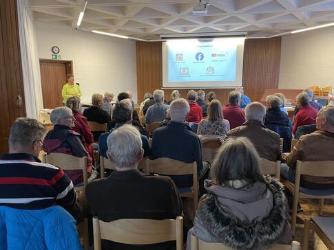 DIe &uuml;ber 30 Teilnehmenden sitzen und schauen auf die Endfolie der Pr&auml;sentation, die auf einer Leinwand gezeigt wird.
