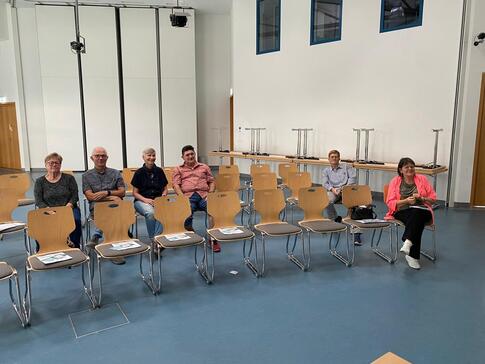 In einem gro&szlig;en Veranstaltungssaal im Rathaus Wiedemar sitzen sechs Personen auf zwei Stuhlreihen und blicken nach vorne in die Kamera.