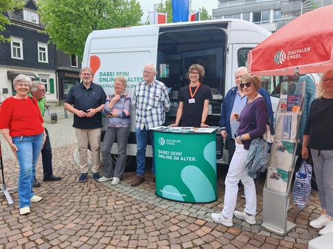 Mehrere Personen stehen um das Infomobil herum und blicken in die Kamera.